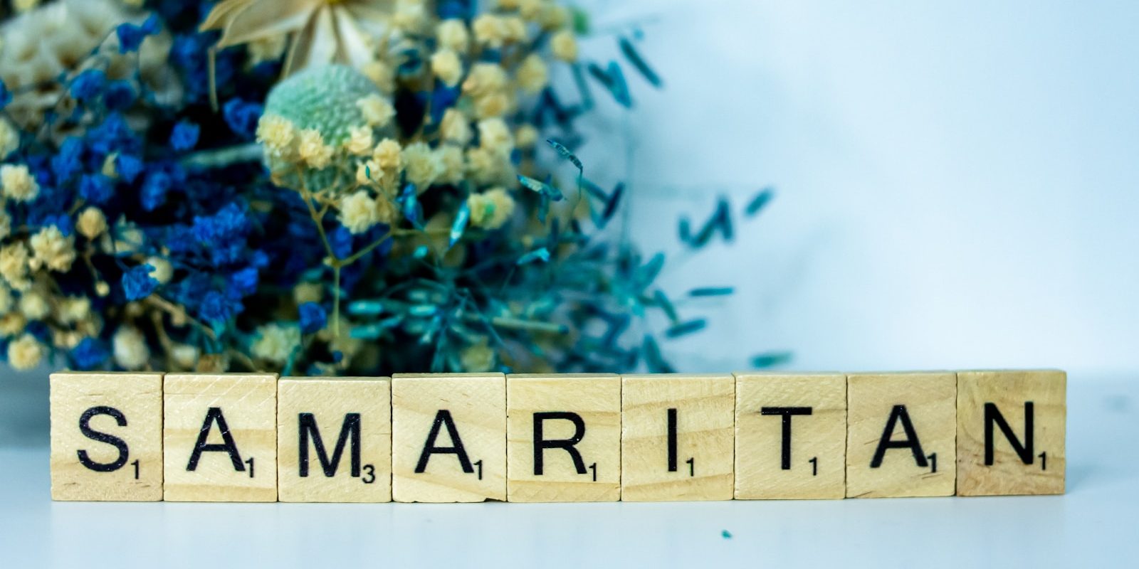 a wooden block that says samaritan next to a bouquet of flowers